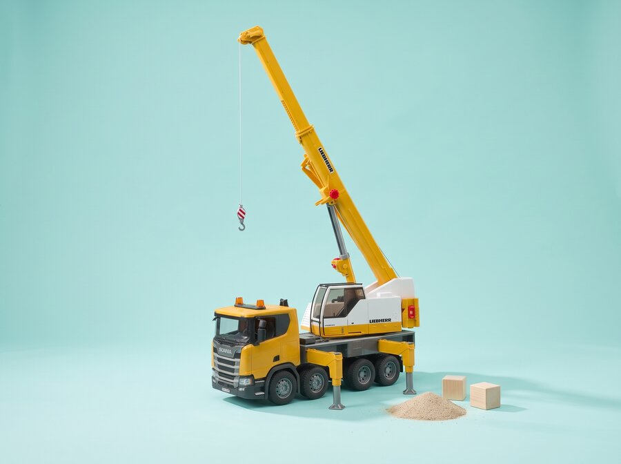 Yellow Bruder toy crane on a turquoise play scene